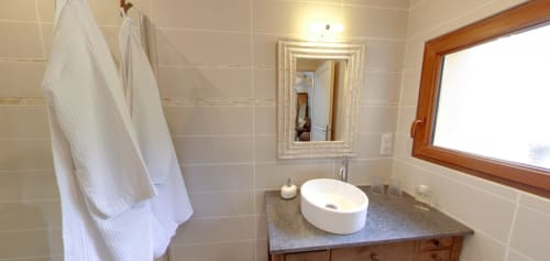 Modern bathroom at Aux Prés Du Berry B&B in Chavin with round sink, mirror, and natural light