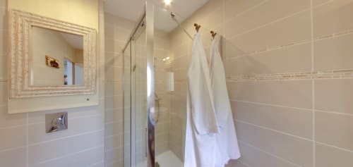 Modern ensuite bathroom at Aux Prés Du Berry B&B with glass shower enclosure, framed mirror, and white towels in Chavin,