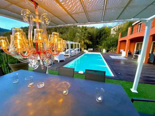 Terrasse de piscine luxe Villa Colina avec lustre en cristal, piscine turquoise et villa orange à Mandelieu-la-Napoule