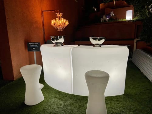 Villa Colina event space with elegant white bar counter, crystal chandelier, and green courtyard in Mandelieu