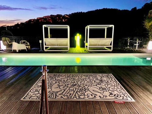 Terrasse piscine luxe Villa Colina au crépuscule avec lits à baldaquin illuminés, tapis motifs et lumières du village en colline