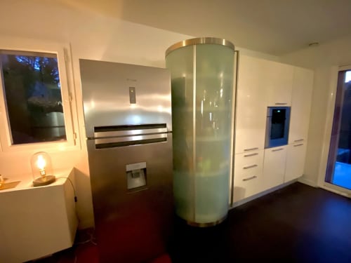 Cuisine moderne de la Villa Colina à Mandelieu avec électroménagers en acier inoxydable et élément cylindrique en verre dépoli