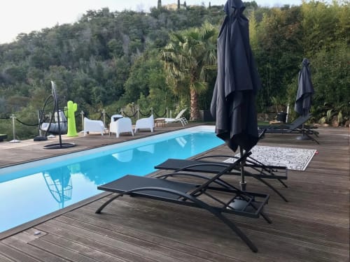 Terrasse piscine Villa Colina avec transats, parasols noirs et vue sur le jardin méditerranéen de Mandelieu-la-Napoule