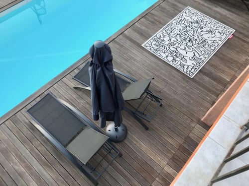 Coin détente au bord de la piscine à Villa Colina avec transat, parasol et livre de coloriage sur terrasse en bois