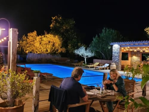 Couple dînant au bord de la piscine illuminée de l'hôtel Le Maquis Plage à Poggio-Mezzana, ambiance soirée
