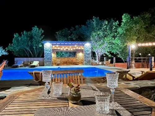 Piscine de luxe du Maquis Plage illuminée la nuit, avec bungalow, transats et arbres à Poggio-Mezzana