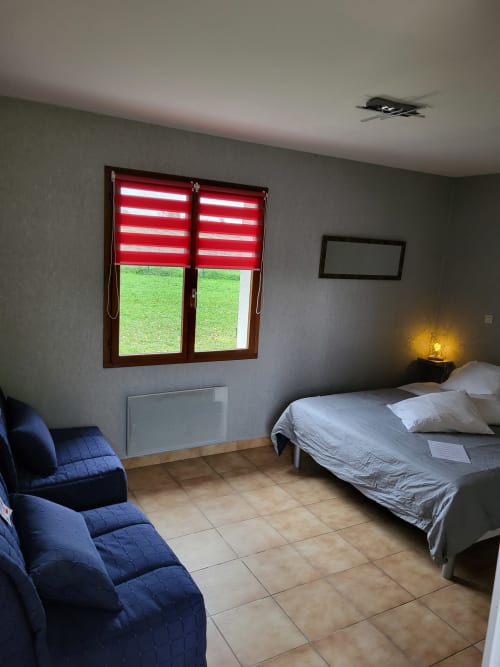 Spacieuse chambre quadruple à l'Hôtel Cheverny La Vie Est Belle avec vue sur jardin, fauteuils bleus, lit et fenêtre à rayures rouges