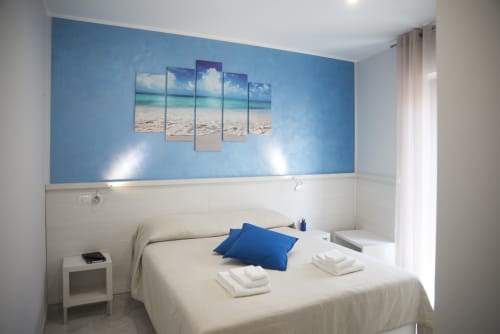 Camera luminosa del B&B La Pigna con parete azzurra, quadri tematici marini e letto confortevole con cuscino blu