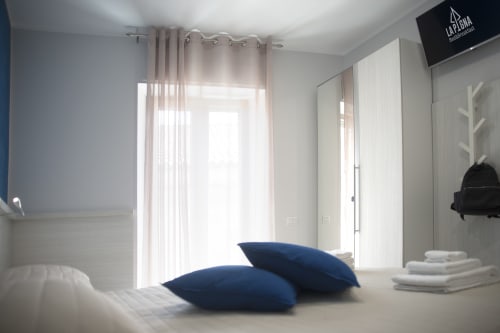 Camera luminosa del B&B La Pigna a Filiano con cuscini blu, biancheria bianca e arredamento moderno