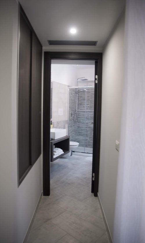 Corridoio moderno che conduce al bagno di B&B La Pigna a Filiano con porta in vetro a cornici nere e arredi contemporanei