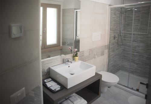 Bagno moderno della B&B La Pigna a Filiano con lavabo bianco, doccia in piastrelle grigie e specchio