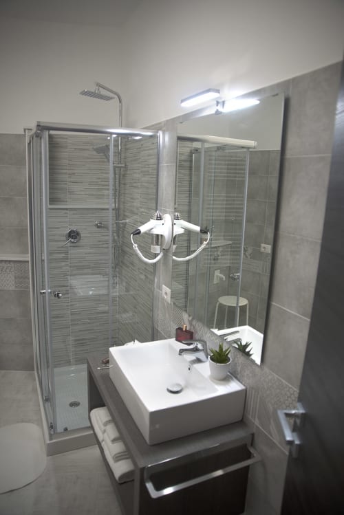 Bagno moderno del B&B La Pigna a Filiano con doccia walk-in, lavabo in ceramica bianca e illuminazione dello specchio