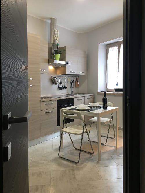 Cucina moderna con tavolo da pranzo presso B&B La Pigna a Filiano, Italia. Mobili in legno chiaro, forno nero e sedie pieghevoli.