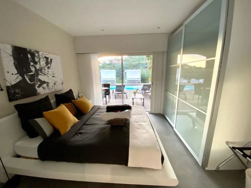 Chambre moderne à la Villa Colina B&B à Mandelieu-la-Napoule avec lit foncé, oreillers jaunes et accès à la terrasse avec vue mer