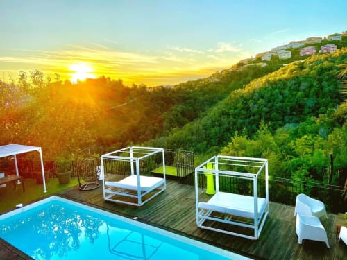 Vue du coucher de soleil sur la terrasse de la piscine de Villa Colina avec lits de jour blancs surplombant la vallée luxuriante à Mandelieu-la-Napoule