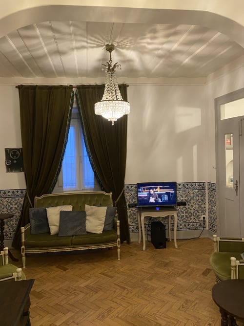 Elegant guest room at Patio Da Villa with green canopy bed, crystal chandelier, and ornate wallpaper in Coruche