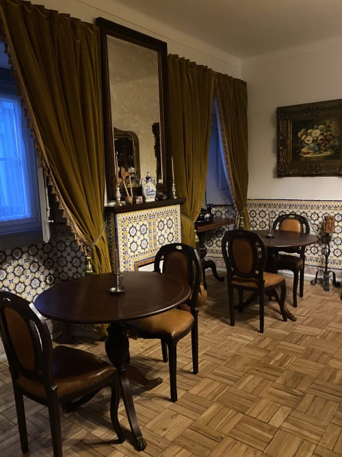 Elegant dining room at Patio Da Villa guesthouse in Coruche with round tables, black chairs, gold curtains, and decorative