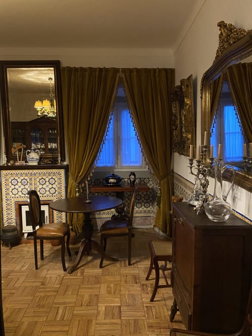 Elegant sitting room at Patio Da Villa with round table, ornate mirrors, olive drapes, and decorative tilework
