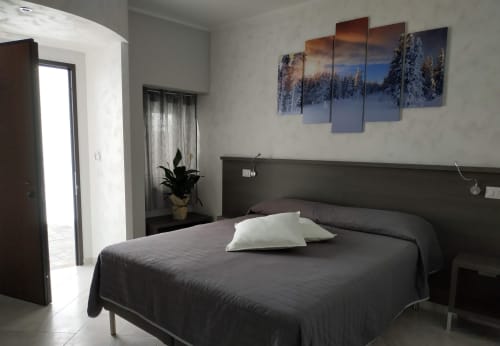 Camera moderna della B&B La Pigna a Filiano con letto scuro, cuscini bianchi e opere d'arte paesaggistica invernale