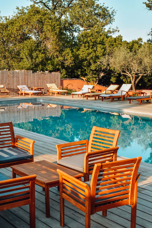 Plage du Maquis au bord de la piscine avec eau turquoise, chaises longues en bois et arbres méditerranéens à Poggio-Mezzana