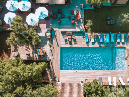 Vue aérienne de la piscine de l'hôtel Le Maquis Plage, transats, parasols et jardins tropicaux à Poggio-Mezzana