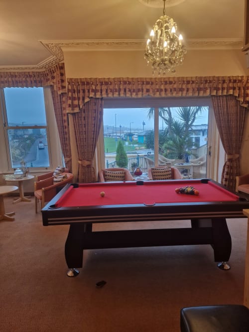 Luxurious billiards room at The Sands Hotel Paignton with red pool table, crystal chandelier, and coastal views