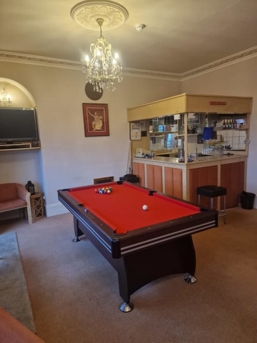 Game room at The Sands Hotel Paignton with pool table, bar, TV, and crystal chandelier