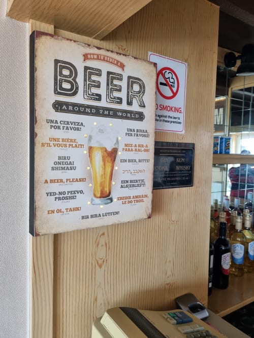 Vintage beer ordering sign at The Sands Hotel Paignton displaying how to order beer in multiple languages with a pint glass