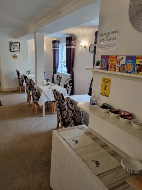 Dining room at The Sands Hotel in Paignton with tables, patterned chairs, breakfast cereals display, and food allergy signage