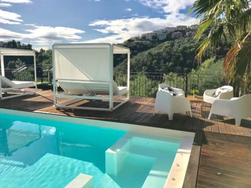 Piscine et terrasse de la Villa Colina avec chaises longues, daybed et vue sur les collines à Mandelieu-la-Napoule