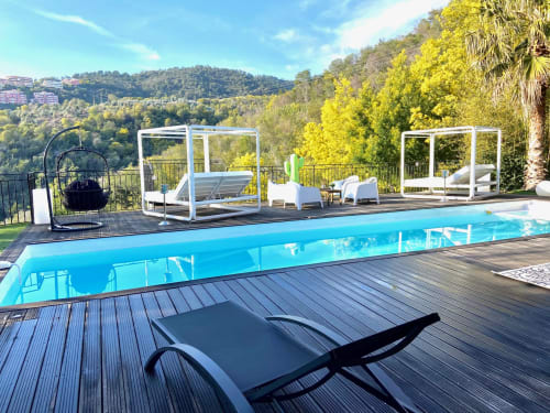 Espace piscine luxueux à la Villa Colina à Mandelieu avec chaises longues, pergolas blanches et vue sur les collines boisées