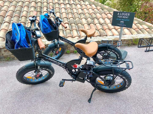Vélos électriques à louer à Villa Colina, Mandelieu-la-Napoule, avec paniers bleus et selles marron près de la terrasse