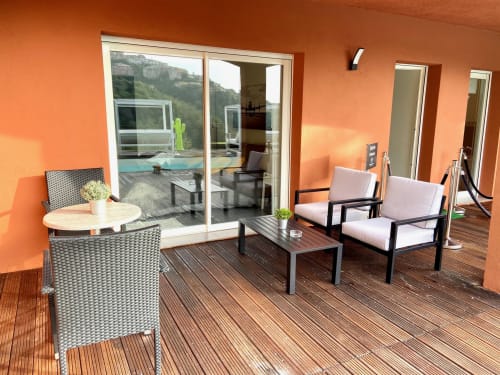 Terrasse moderne de la Villa Colina avec salon, vue sur la piscine et murs orangés à Mandelieu-la-Napoule