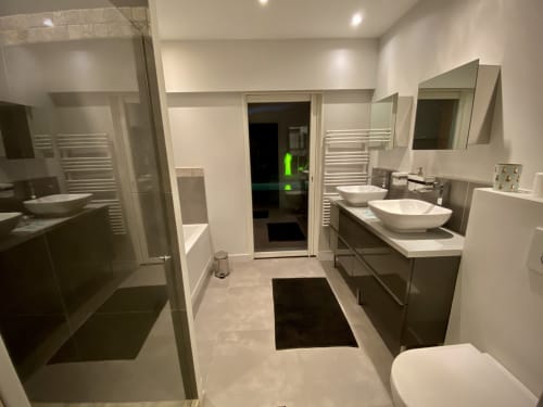 Salle de bains moderne et luxueuse à la Villa Colina avec vasques doubles, douche spacieuse, sèche-serviettes chauffant et équipements contemporains