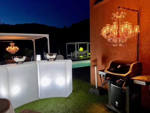 Élégante terrasse extérieure de Villa Colina au crépuscule avec lustres illuminés, sièges cube lumineux et barbecue