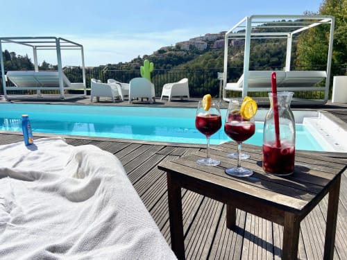 Terrasse piscine luxueuse à la Villa Colina avec boissons rafraîchissantes, chaises longues et vue panoramique sur Mandelieu la Napoule