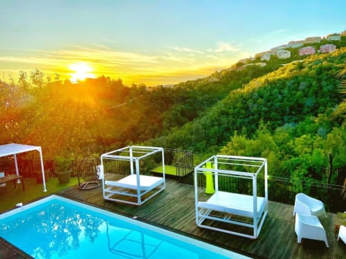 Vue coucher de soleil sur la piscine et la terrasse de Villa Colina dominant la vallée boisée de Mandelieu-la-Napoule