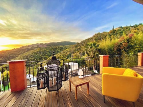 Terrasse de Villa Colina avec chaise jaune, vue coucher de soleil sur les collines de Mandelieu-la-Napoule et le paysage méditerranéen