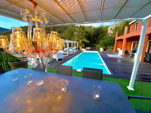Terrasse de luxe au bord de la piscine de la Villa Colina : lustre en cristal, piscine turquoise et villa orange à Mandelieu-la-Napoule