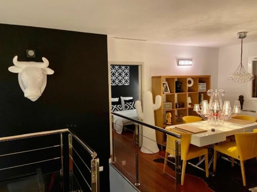 Espace de vie et salle à manger ouverte à Villa Colina avec chaises jaunes, étagères en bois et suspension blanche