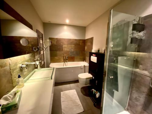 Salle de bain moderne du gîte Villa Colina avec vasque double, baignoire, douche à l'italienne et sèche-serviettes électrique, Mandelieu la