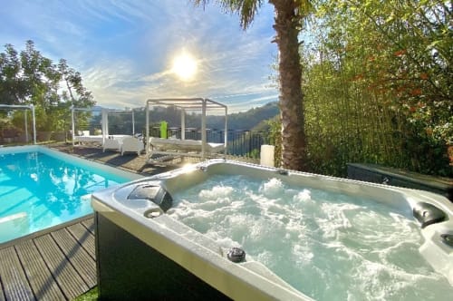 Jacuzzi aux eaux bouillonnantes près de la piscine étincelante de la Villa Colina à Mandelieu-la-Napoule, entouré de palmiers