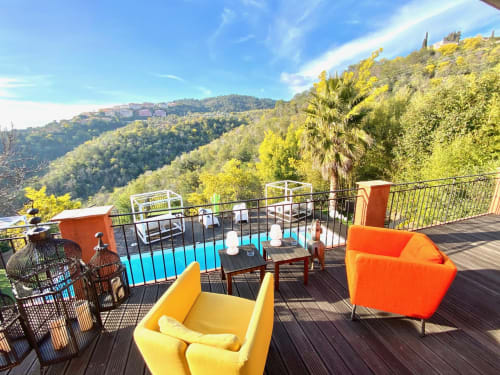 Villa Colina Mandelieu : Terrasse luxe avec sièges colorés, piscine et vue panoramique sur collines boisées