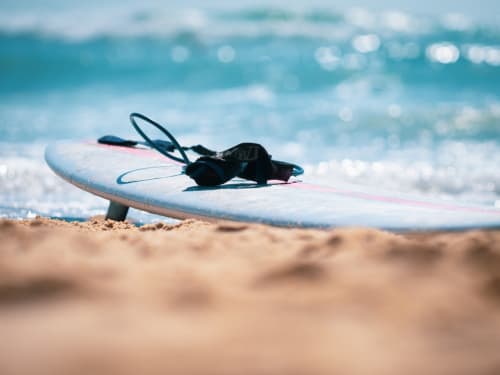 Taula de surf i tratge de neoprè en platja arenosa amb ones oceàniques a Le Manoir Lacustre a Queyrac