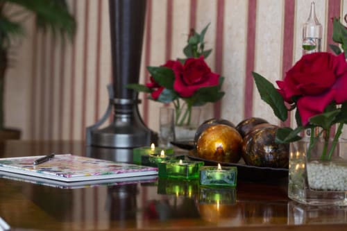 Elegant hotel room decor at The Sands Hotel with red roses, candles, magazines and decorative spheres on table