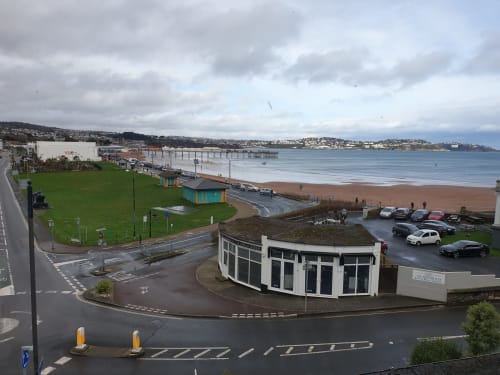 The Sands Hotel beachfront in Paignton with sandy beach, pier, green lawns and seafront buildings