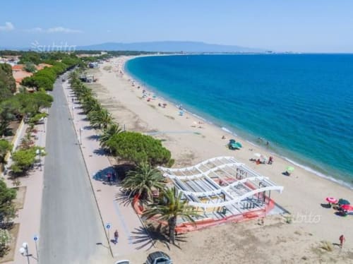 Vue bord de mer de Torre Grande Oristano avec plage de sable, mer Méditerranée turquoise et promenade côtière bordée de palmiers