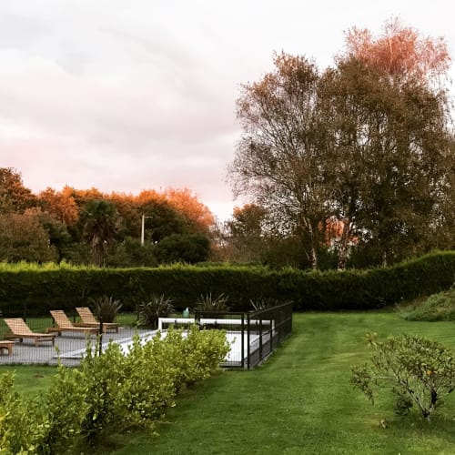 Espace piscine des Gîtes De L'odet avec transats, pelouse verdoyante et arbres d'automne à Clohars-Fouesnant