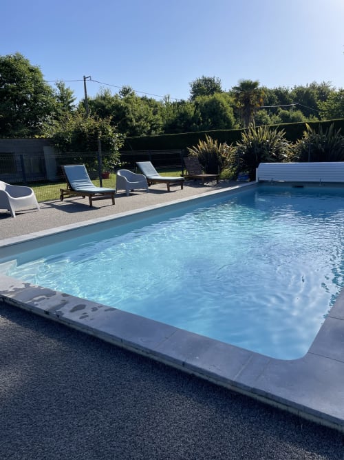 Piscine cristalline aux Gîtes De L'odet à Clohars-Fouesnant avec transats et jardins luxuriants