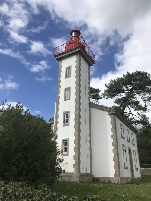 Phare blanc à toit rouge aux Gîtes De L'odet à Clohars-Fouesnant, entouré de verdure